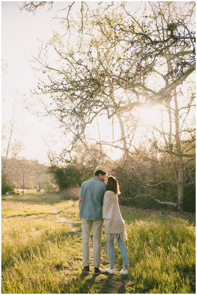 couple cuddling during golden hour engagement photo at park engagement session location 