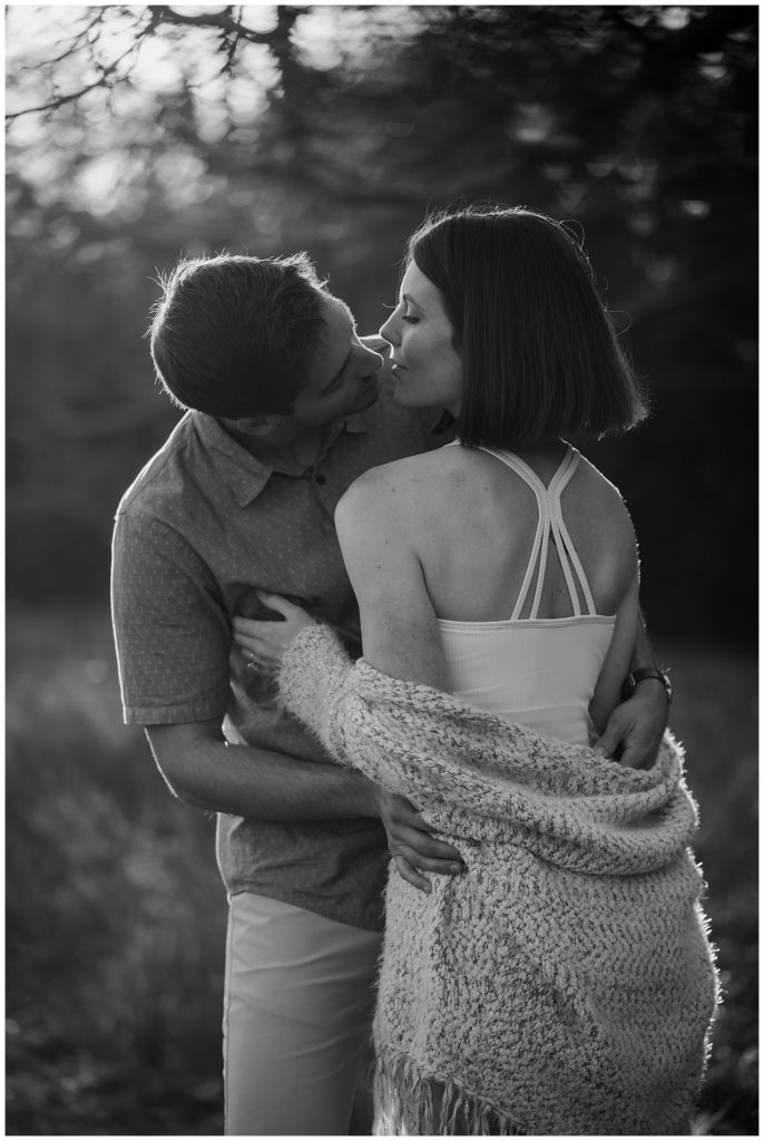 couple cuddling during golden hour engagement photo at beach engagement session location - black and white engagement photos