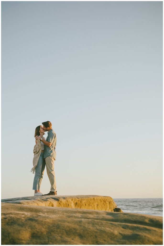 man holding woman in beach seaside engagement session location - golden hour couple's photos