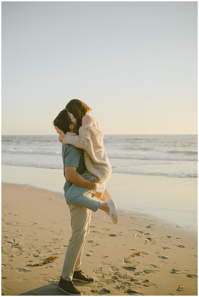 man holding woman in beach seaside engagement session location 